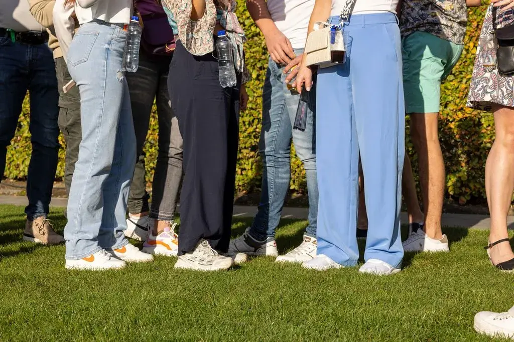 Groep mensen op het gras met bekers en flessen in Mr Cliprs aan hun broek