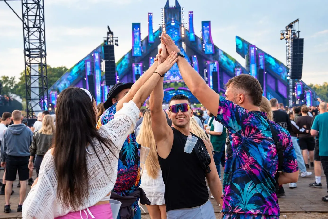 Festivalgangers geven elkaar een high five, met een beker in een Mr Clipr aan de broek
