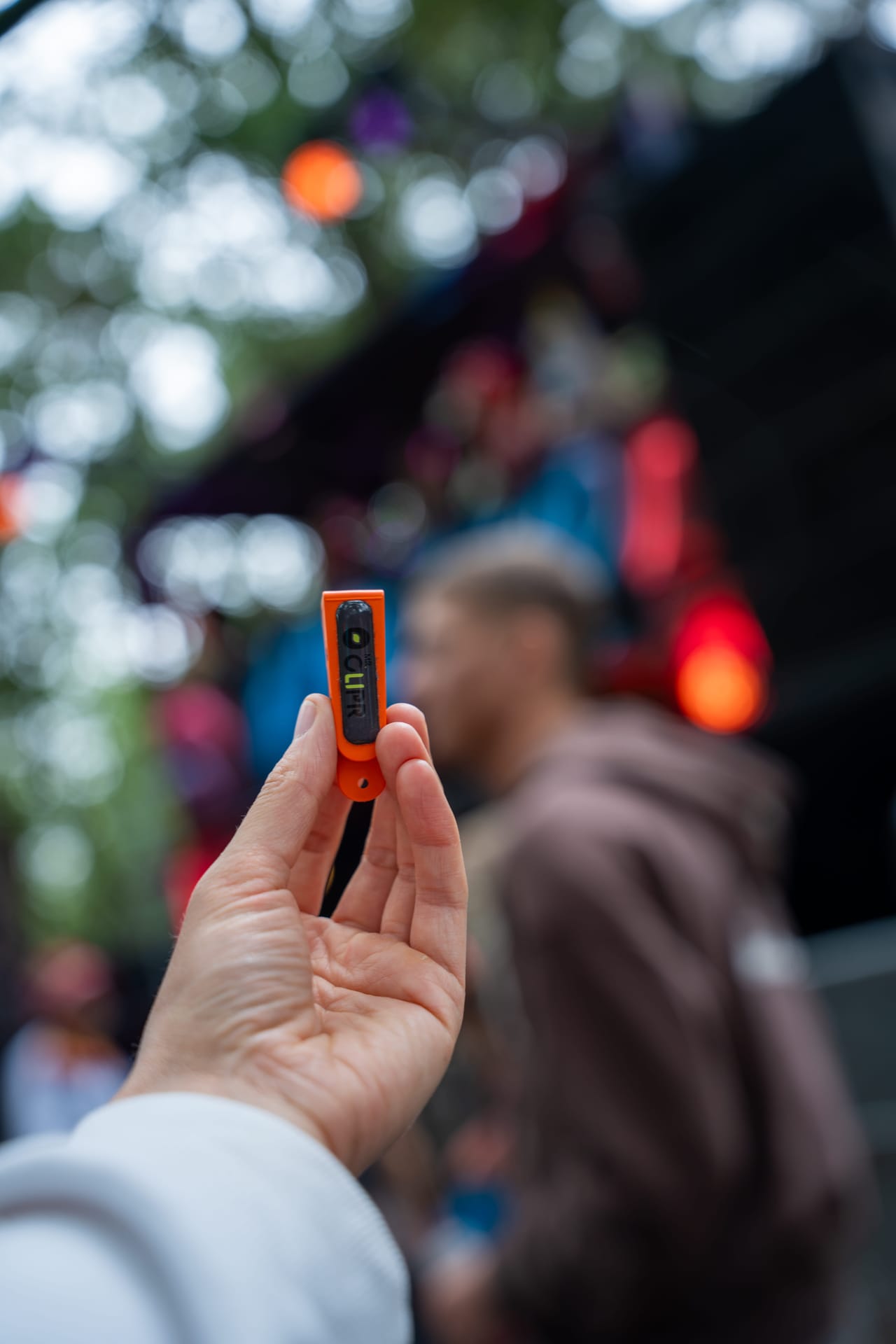 Oranje Mr Clipr in de hand voor een verlicht festivalpodium